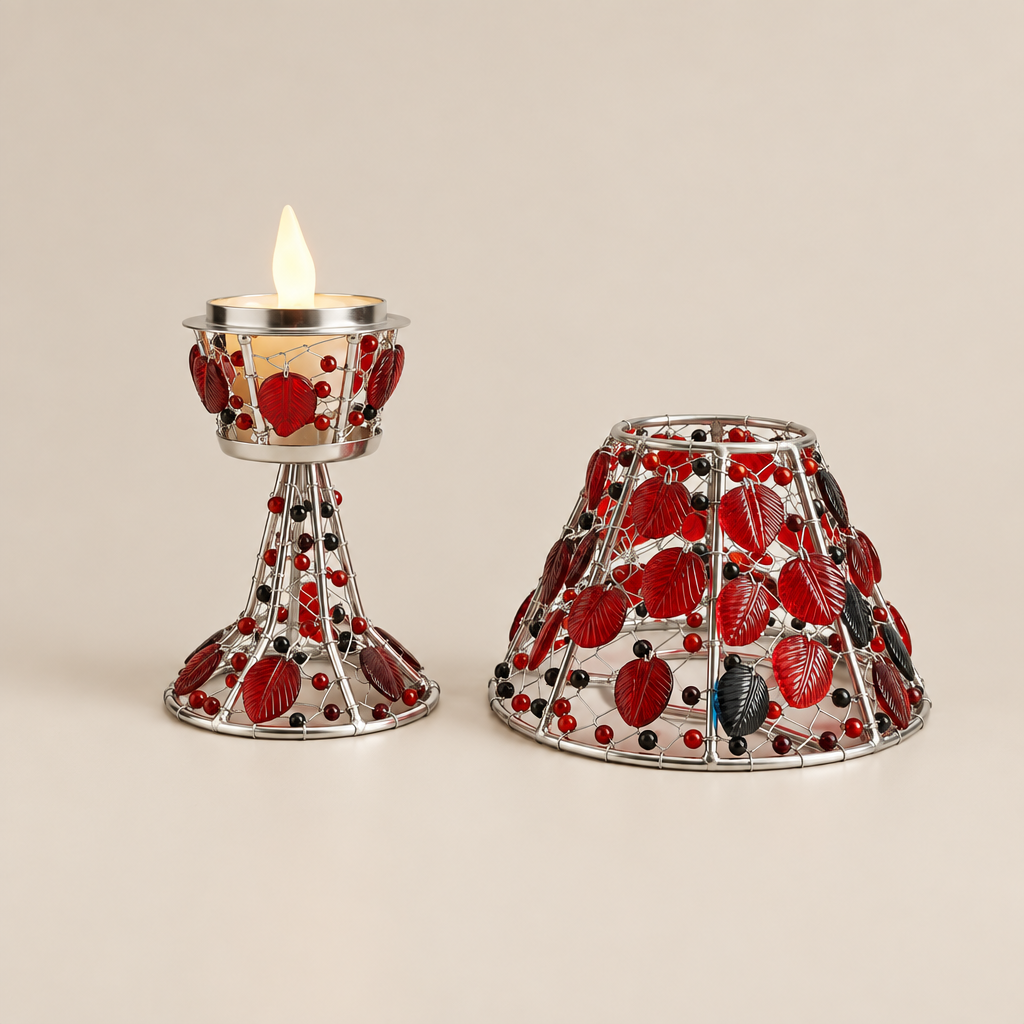 A silver metal candle holder set with red and black berry-patterned glass panels, featuring a lit tealight holder on the left and a matching shade on the right, photographed on a neutral gray background.