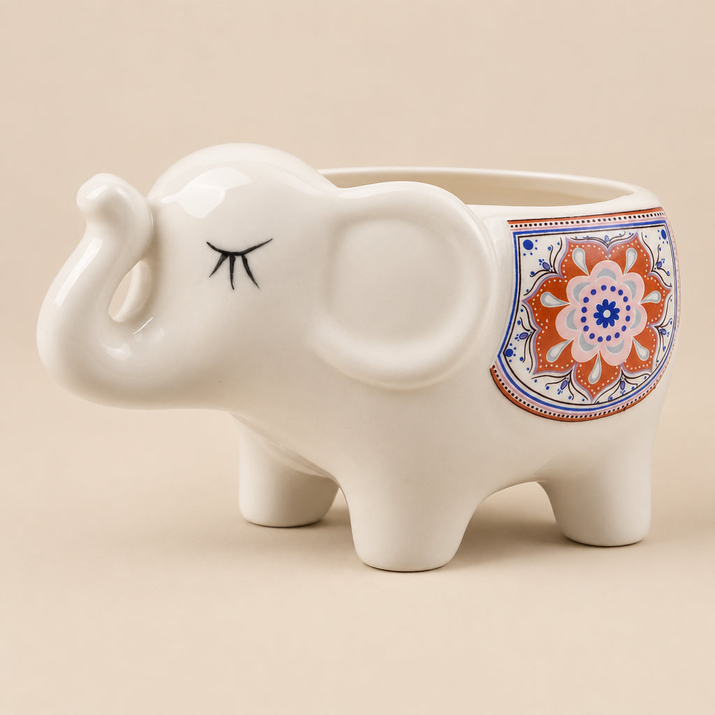 A white ceramic elephant planter with a closed-eye design and a colorful mandala pattern on its side, set against a plain white background.