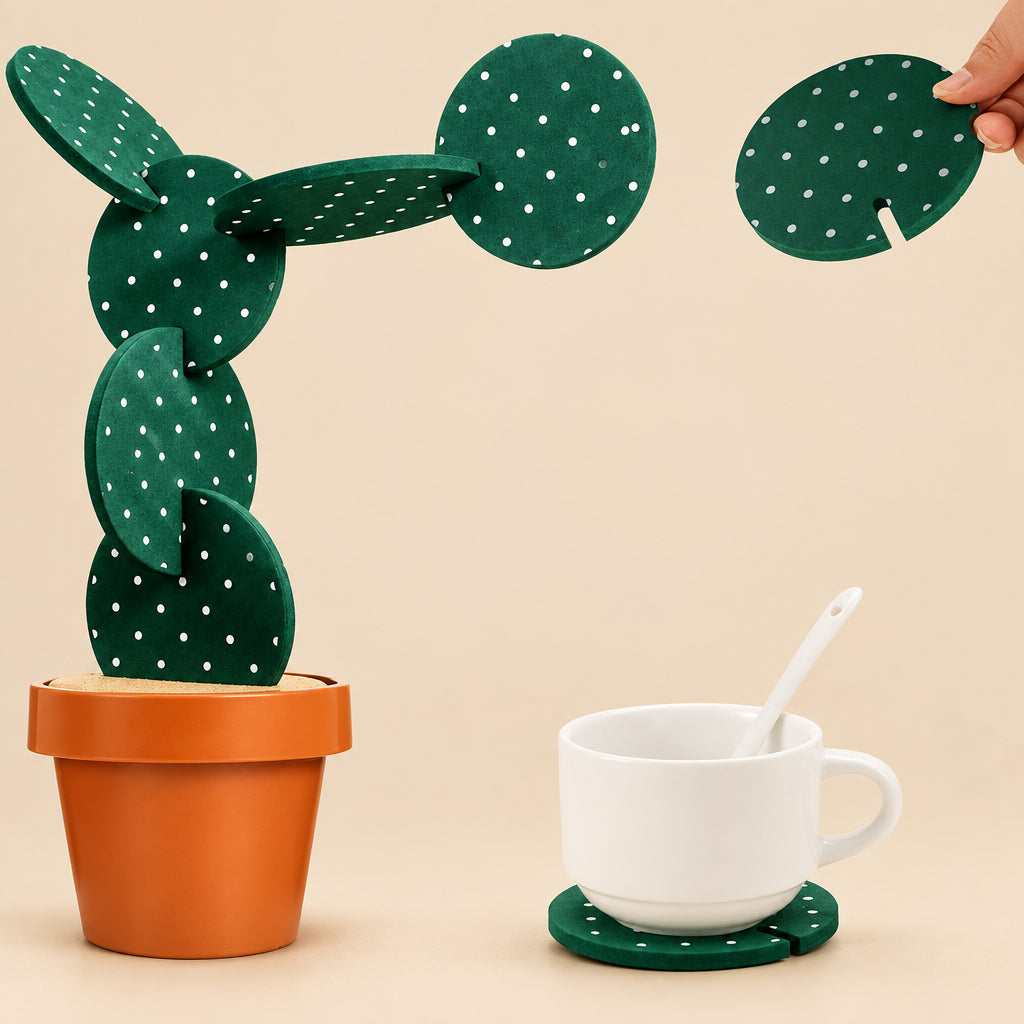 Cactus-shaped coaster with a hand holding another coaster, next to a cup and spoon on a white background.