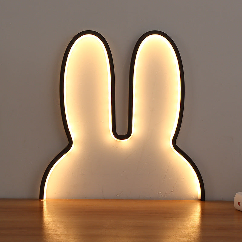 Rabbit-shaped LED night light on a wooden surface with a neutral background